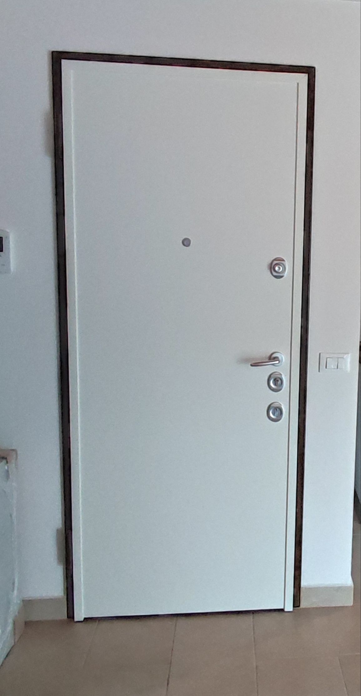 Una porta bianca è seduta in una stanza accanto a un muro.