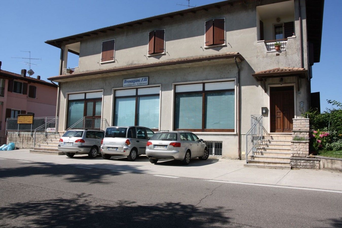 Davanti a un edificio è parcheggiata una fila di auto