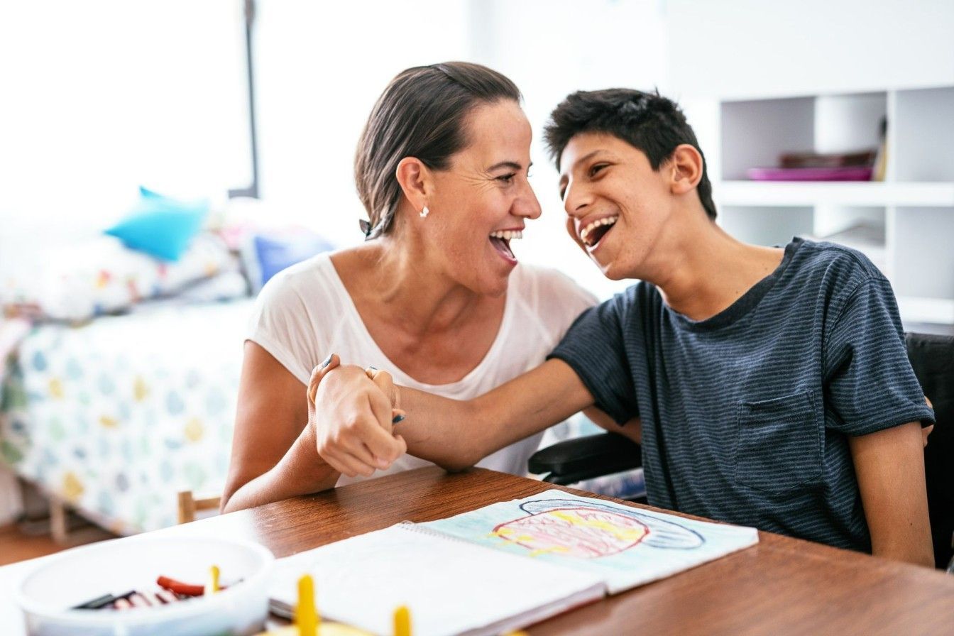 A woman is shaking hands with a boy in a wheelchair at a table.