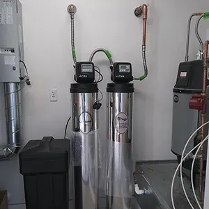 Two tall water softener tanks with gauges and pipes in a utility room