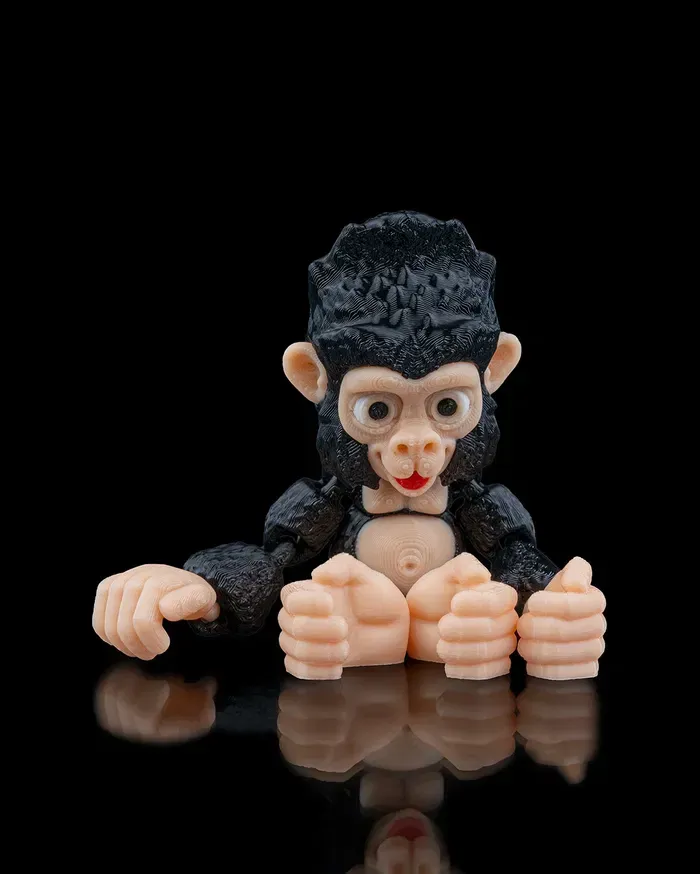 A toy gorilla with a bow tie is sitting on a black surface.