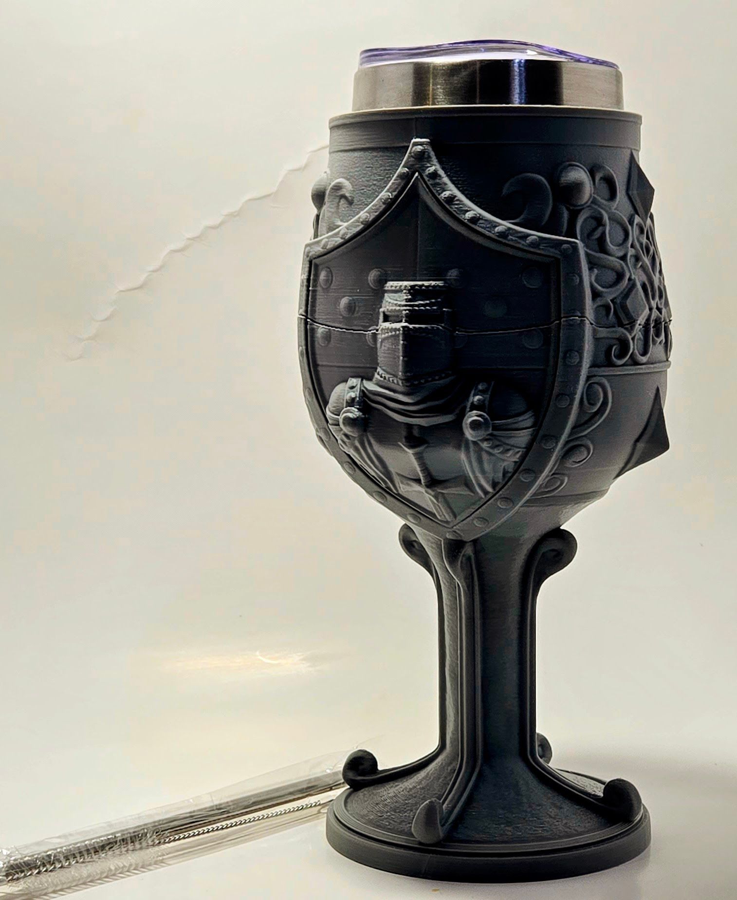 A black goblet with a shield on it is sitting on a table.