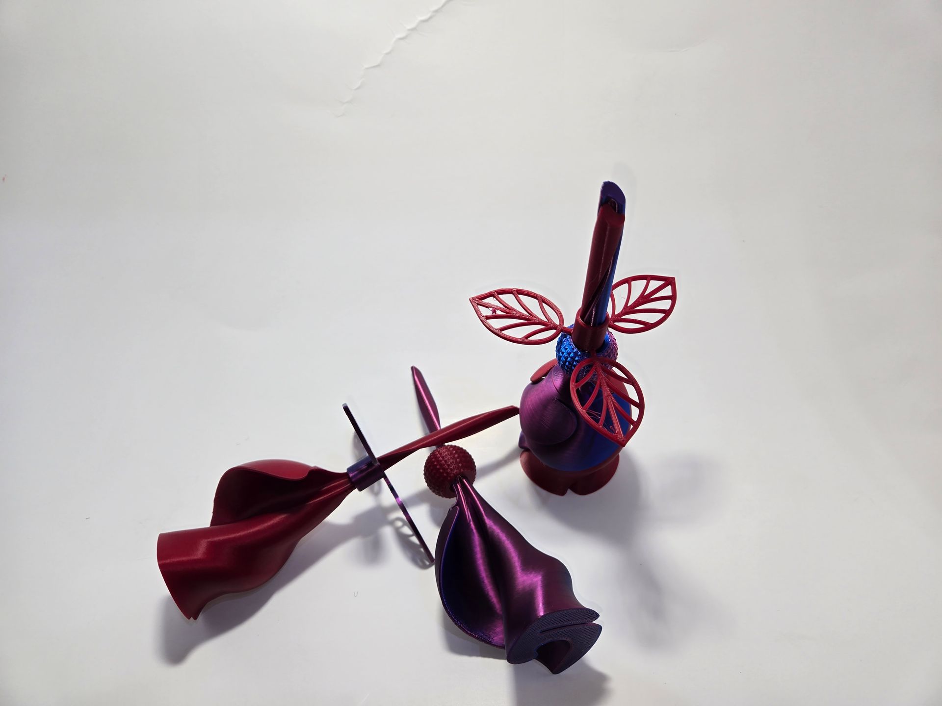 Two purple flowers with red leaves are sitting on a white surface.