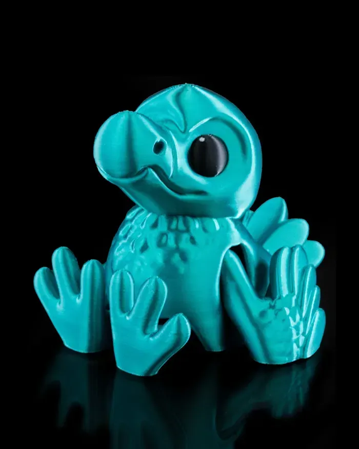 A turquoise figurine of a bird is sitting on a black surface