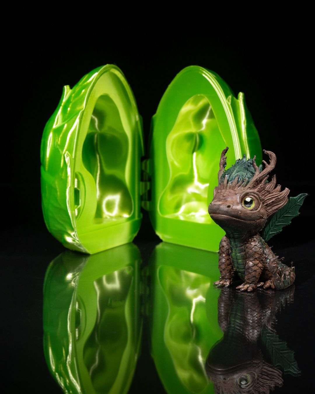 A small figurine of a dragon is sitting next to a green egg.