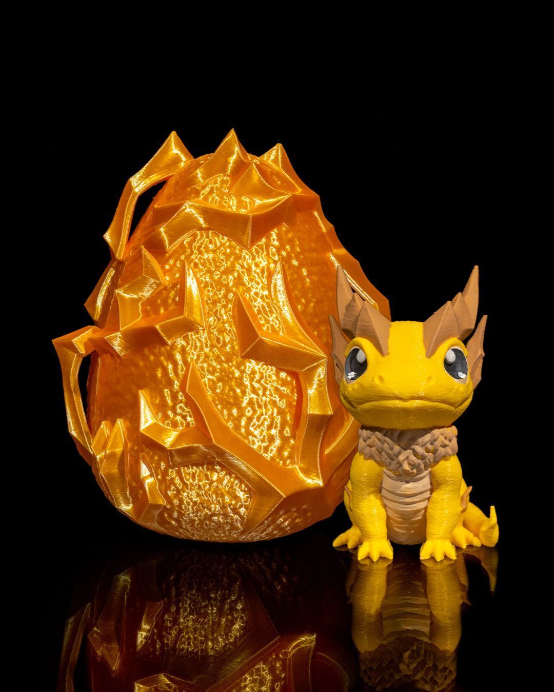 A yellow toy dragon is sitting next to an orange egg.