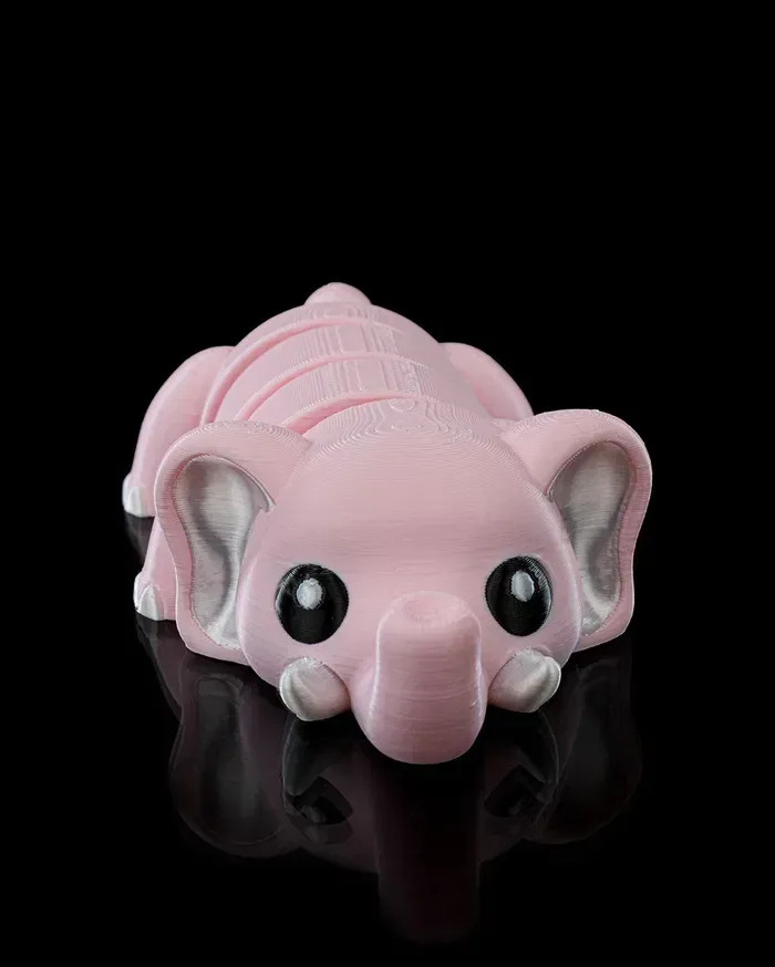 A pink elephant is laying down on a black surface.