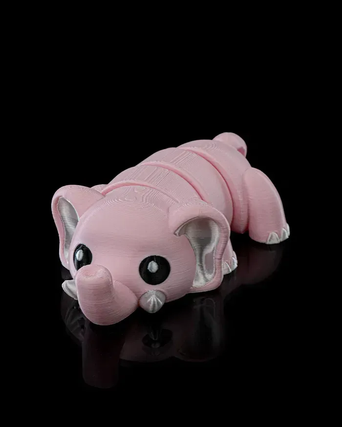 A pink elephant is laying down on a black surface.
