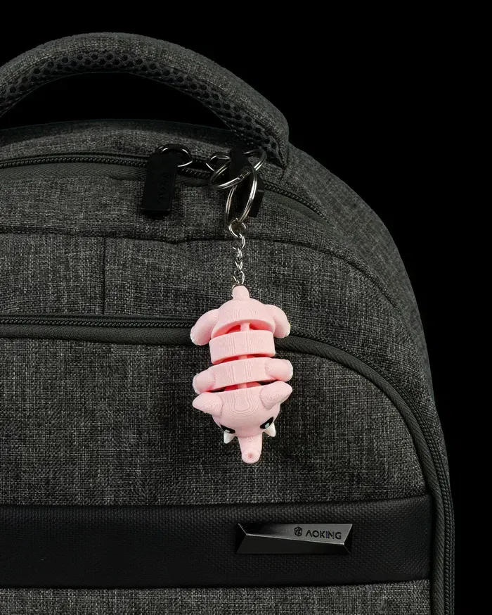 A close up of a backpack with a pink keychain attached to it.