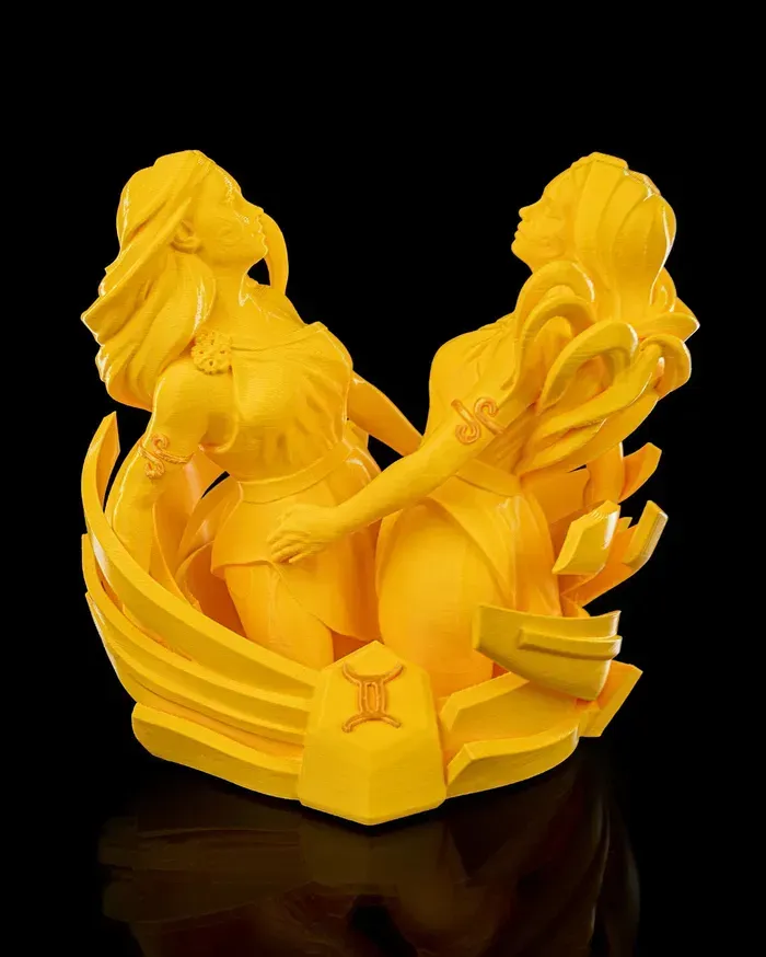 A yellow statue of two women with a zodiac sign in the middle