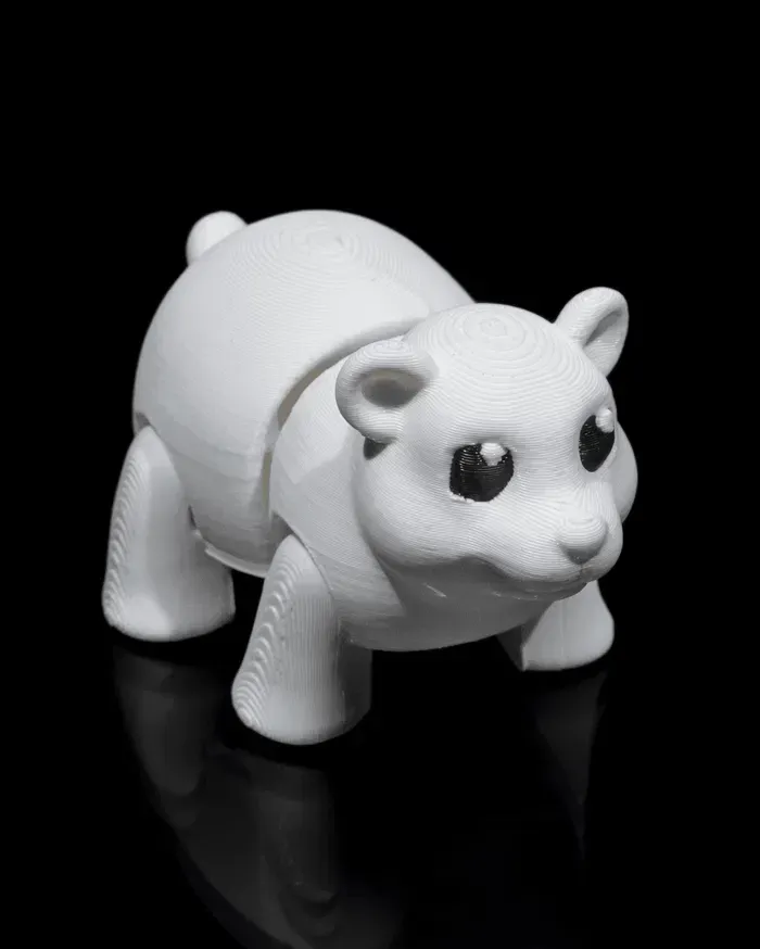 A white toy polar bear is sitting on a black surface.