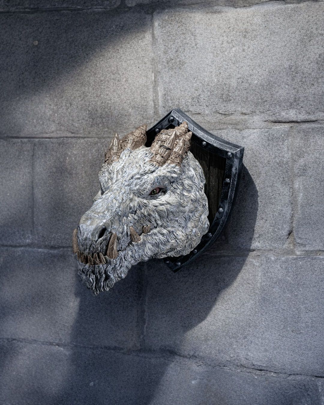 A statue of a dragon 's head is hanging on a wall.