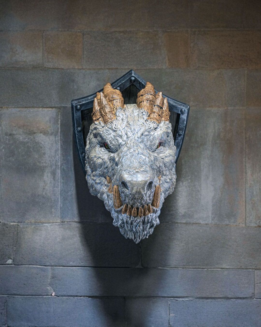 A statue of a dragon 's head is hanging on a wall.