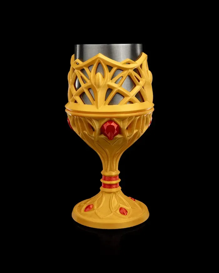 A gold and silver goblet with red stones on a black background.