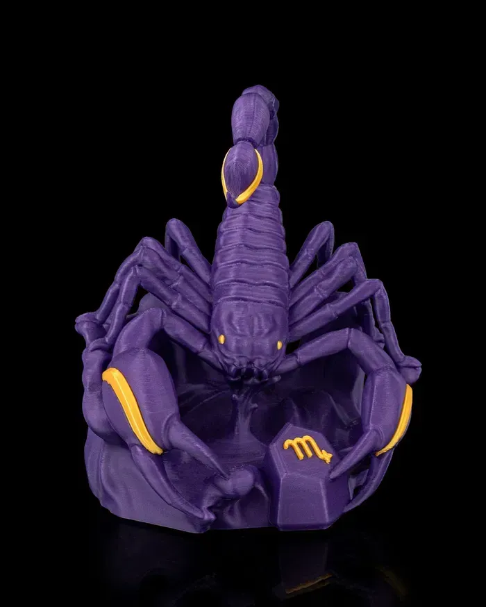 A purple scorpion figurine with a yellow tail is sitting on a black surface.