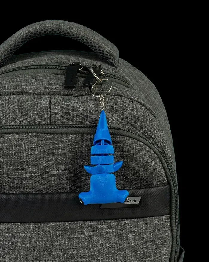 A close up of a backpack with a blue keychain attached to it.