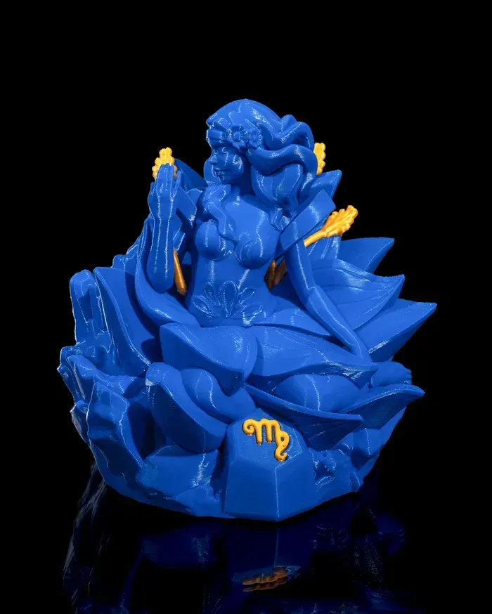 A blue statue of a woman sitting on a rock with the letter m on it.