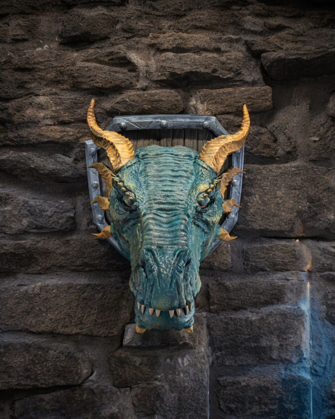 A dragon head with horns is hanging on a stone wall.