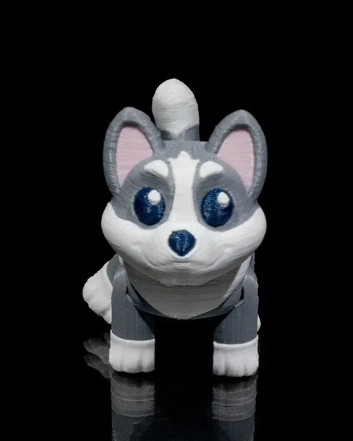 A gray and white husky dog toy is standing on a black surface.