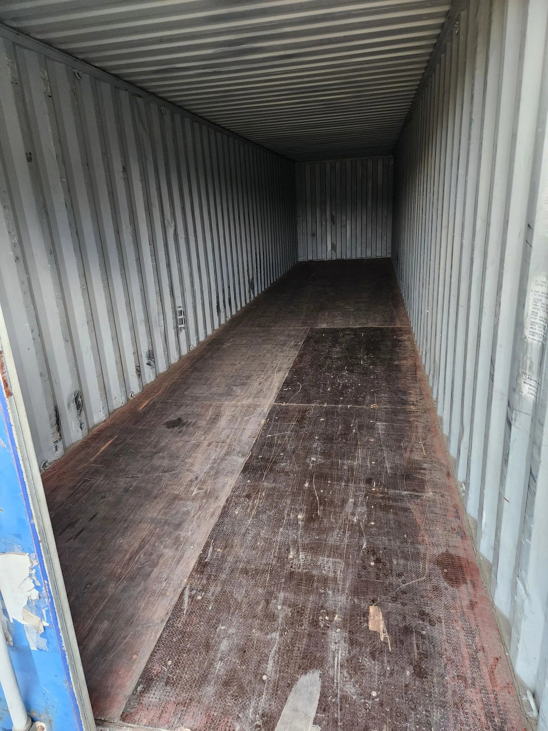 Empty shipping container interior with a dirty, brown floor.