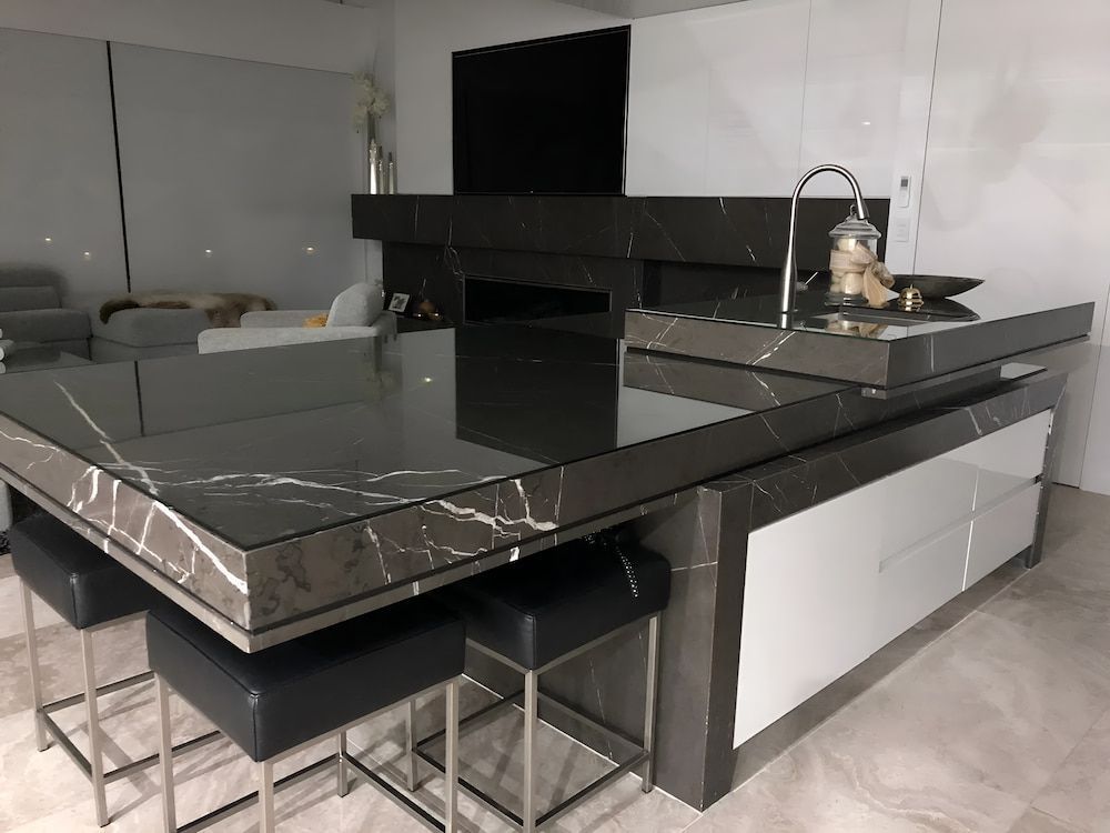 A Kitchen With A Black Marble Countertop And Stools — United Kitchens and Joinery in Albion Park, NSW