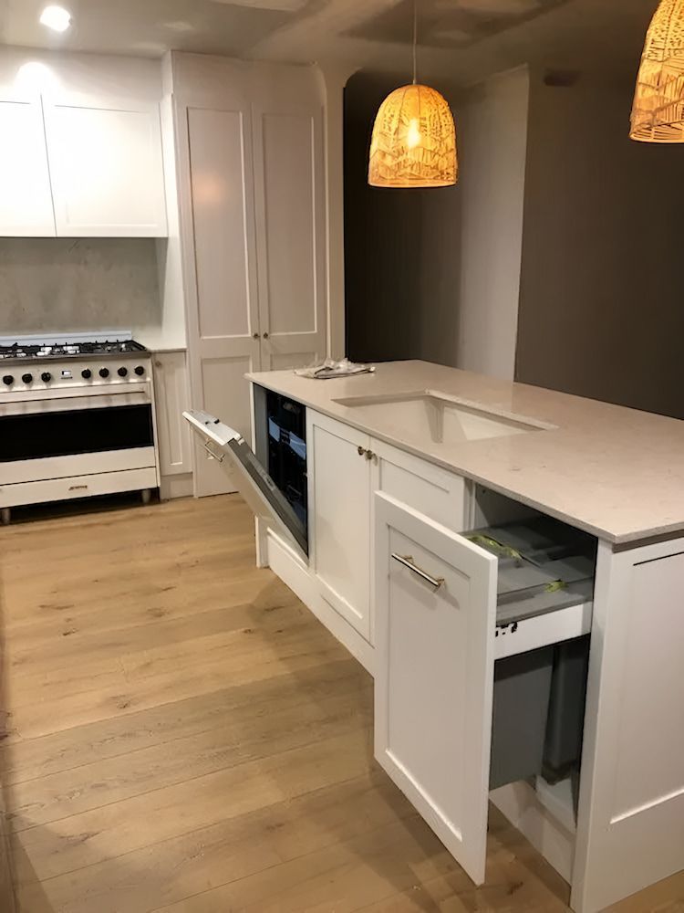 A Kitchen With White Cabinets, A Sink, And A Stove — United Kitchens and Joinery in Oak Flats, NSW