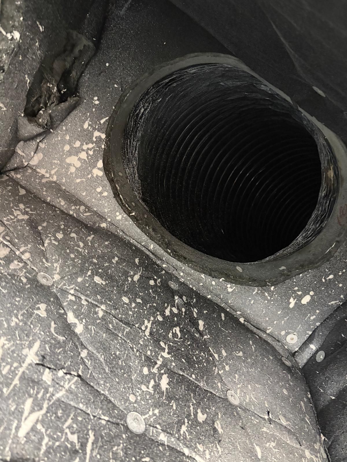 Black corrugated pipe inside a hole in a gray speckled surface.