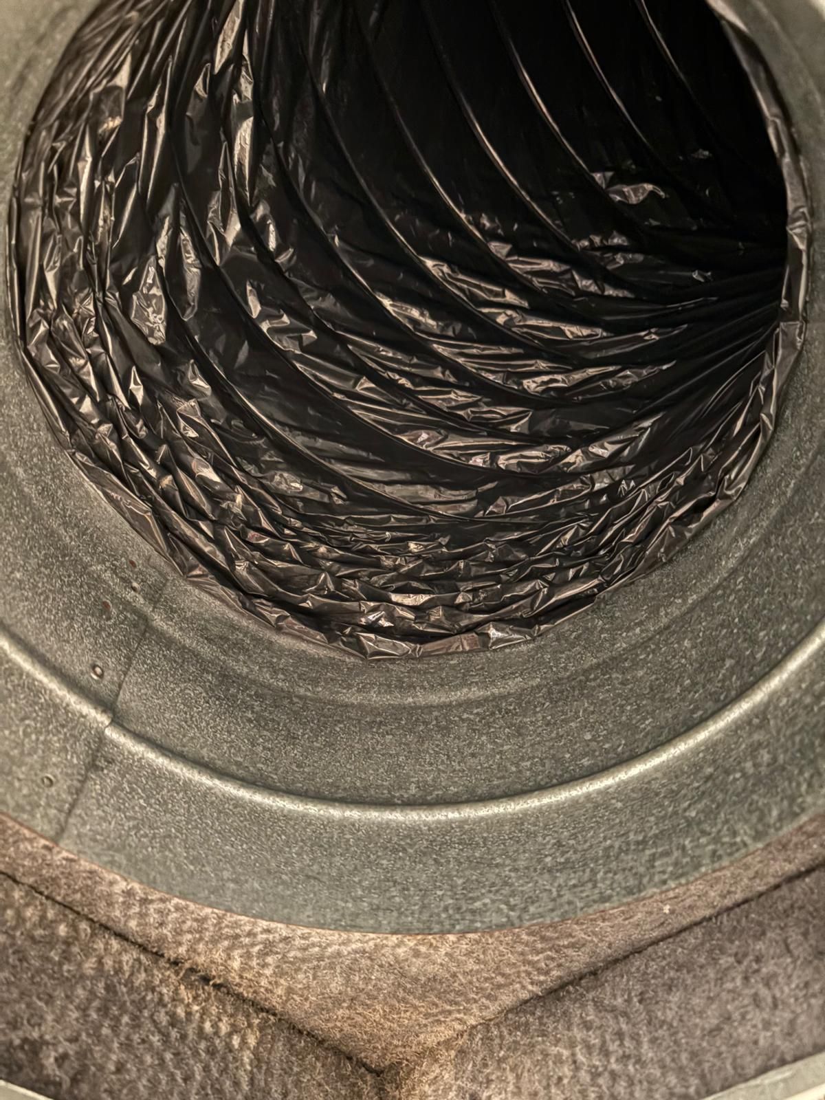 Inside view of a circular air duct with a black, flexible inner duct and gray metal framing.