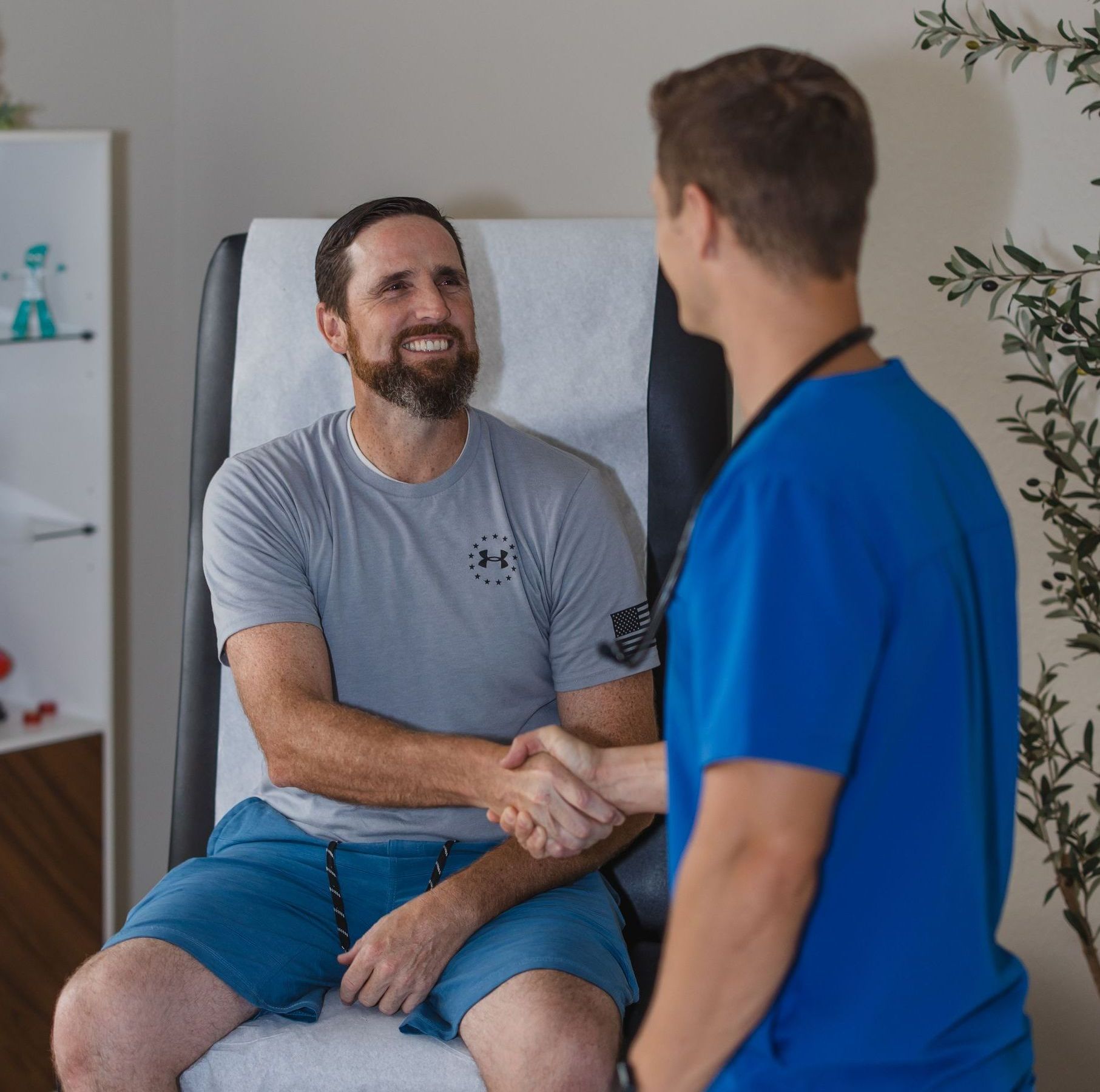 Man shaking hands with healthcare worker in a medical exam room.