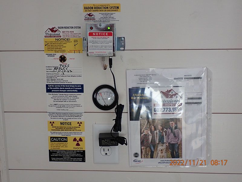 Wall-mounted gas meter and utility warning labels beside a plastic-covered notice on a white wall.