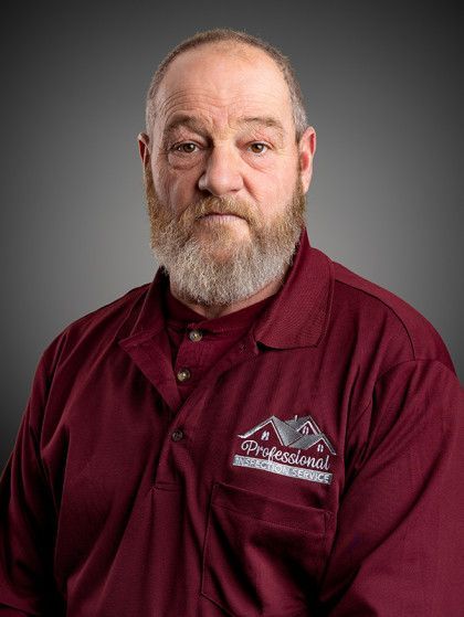 Portrait of a man in a maroon work shirt against a gray background