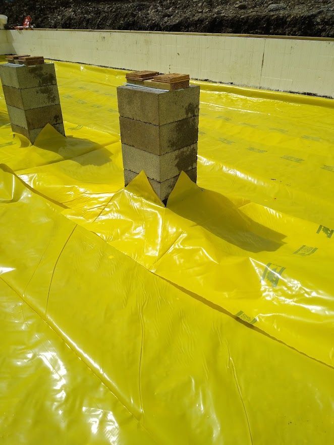 Two stacked cinder blocks on a yellow tarp, with a concrete wall in the background.
