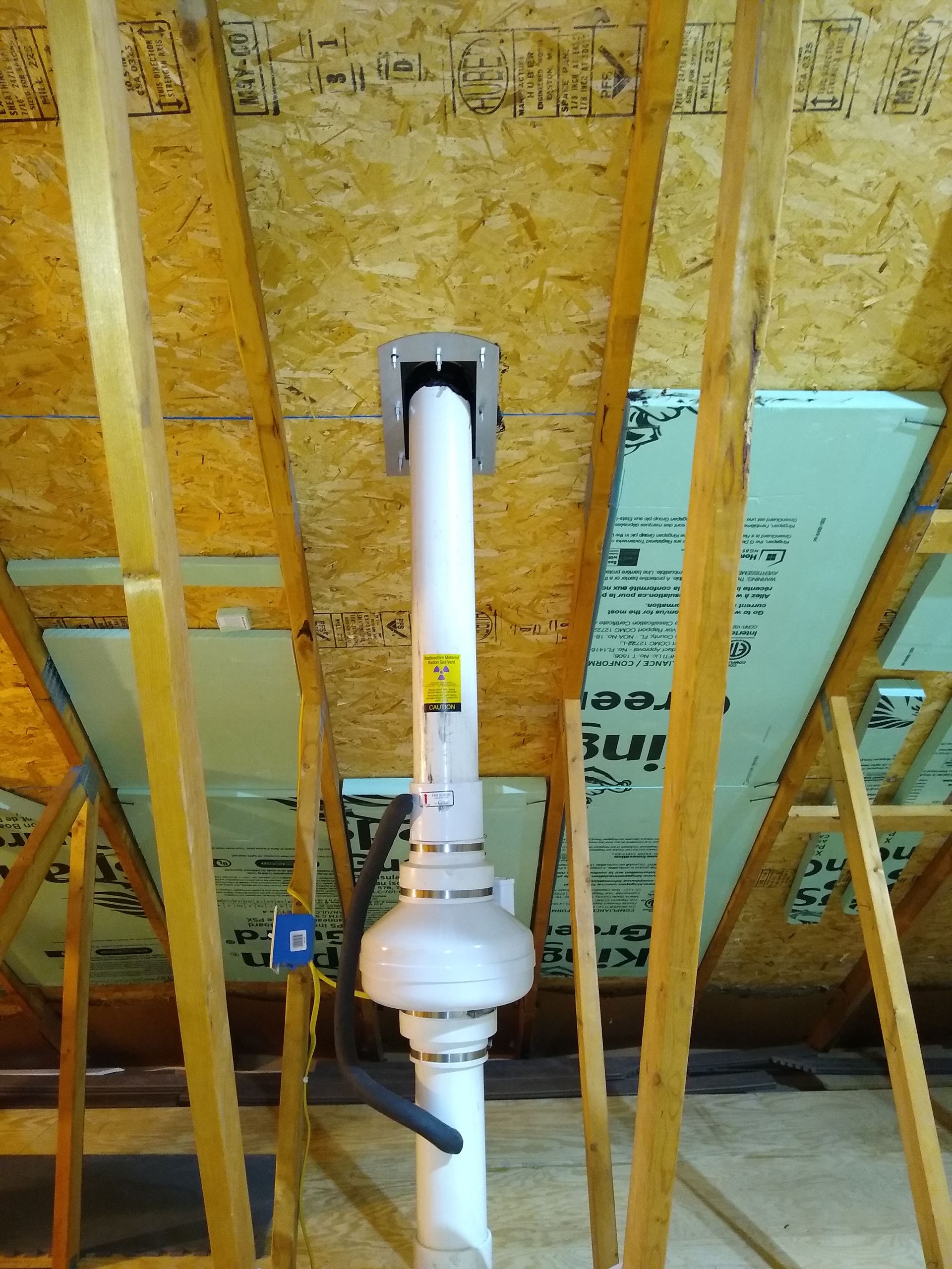 White plumbing vent pipe in a framed wall under construction with exposed plywood sheathing.