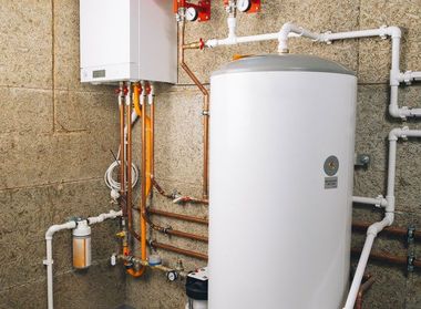White water heater and boiler with exposed copper and PVC pipes in a utility room