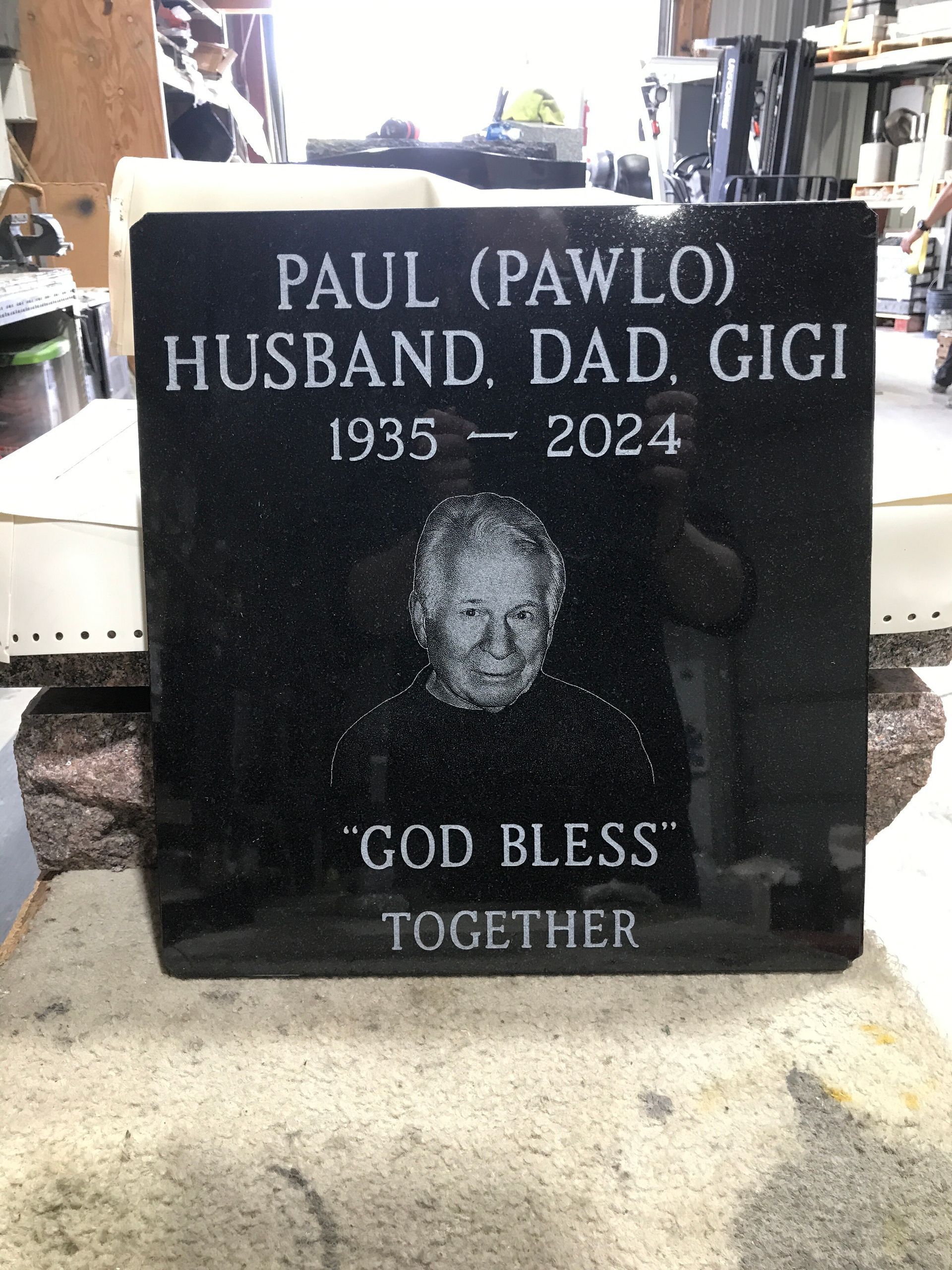 Black granite memorial headstone for Paul (Pawlo), husband, dad, and Gigi, 1935–2024, with “God Bless Together.”