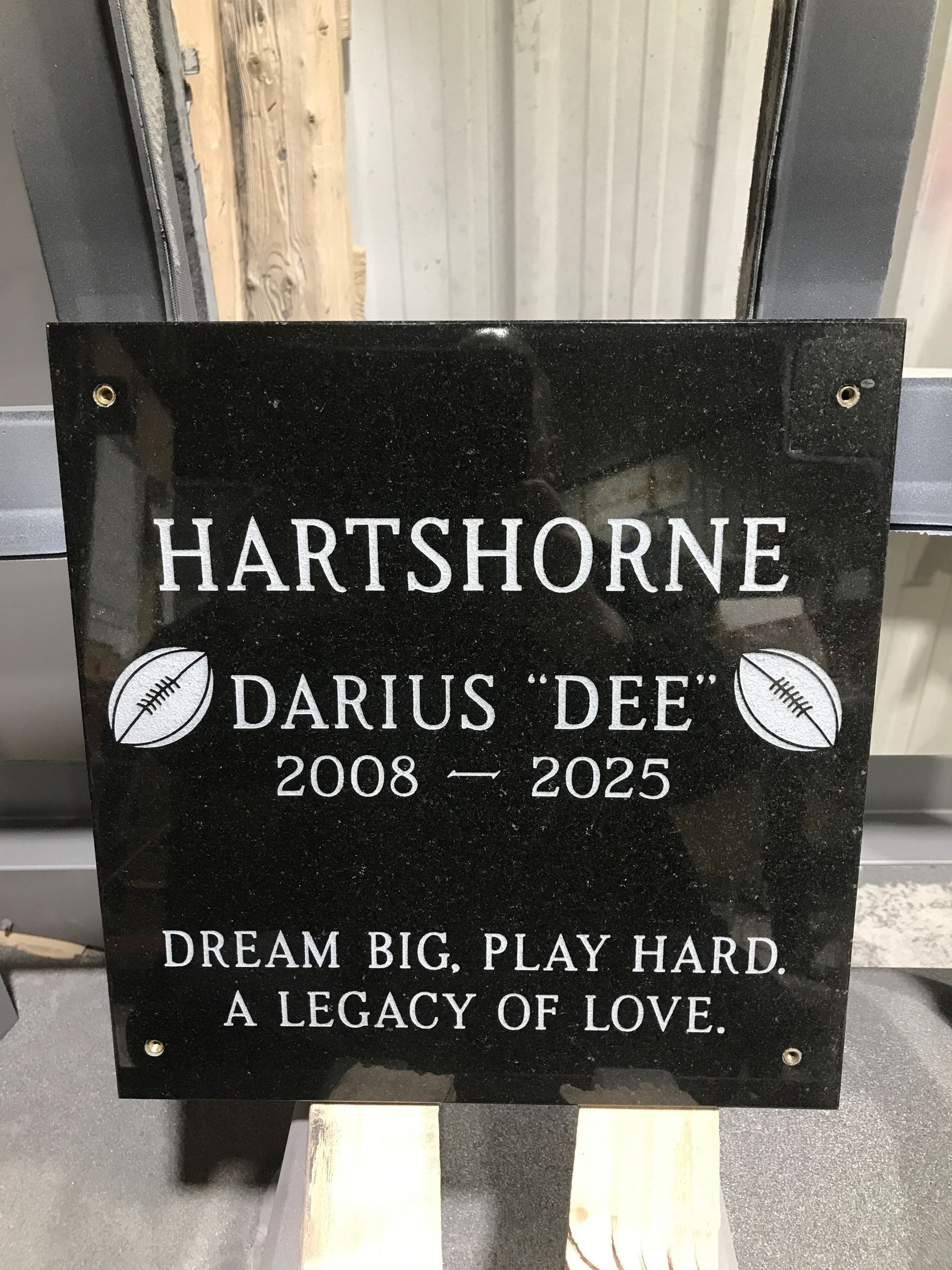 Black memorial plaque for Darius “Dee” Hartshorne, 2008–2025, with “Dream big, play hard, a legacy of love.”