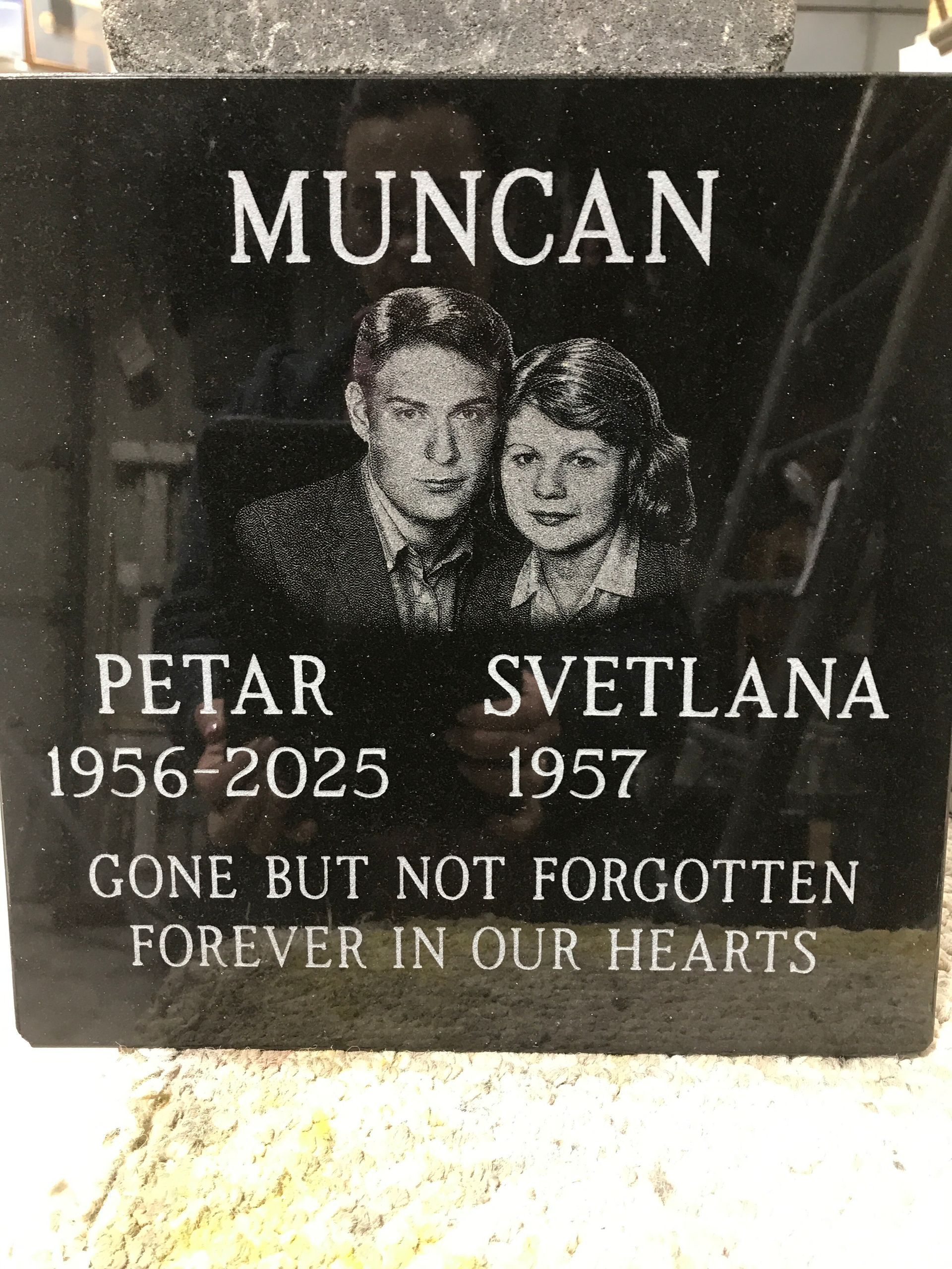 Black memorial plaque with portrait and text: “MUNCAN,” Petar 1956–2025, Svetlana 1957, “Gone but not forgotten.”