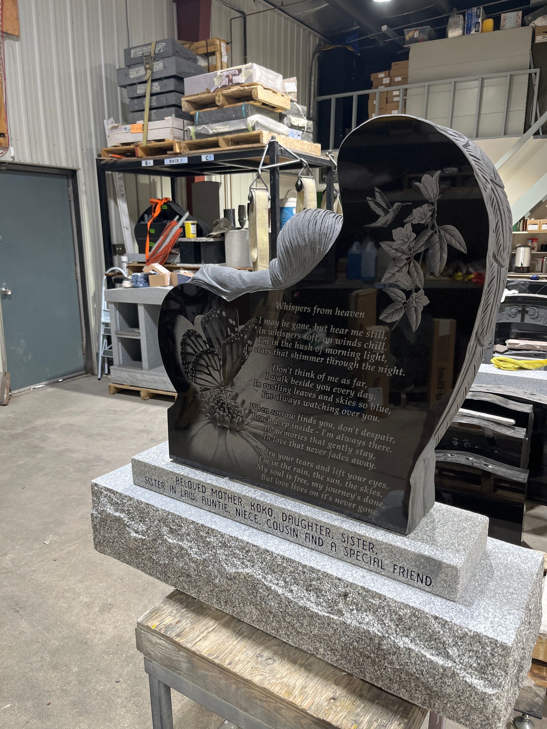 Black polished stone sculpture on a granite base in a workshop, with shelves and tools in the background