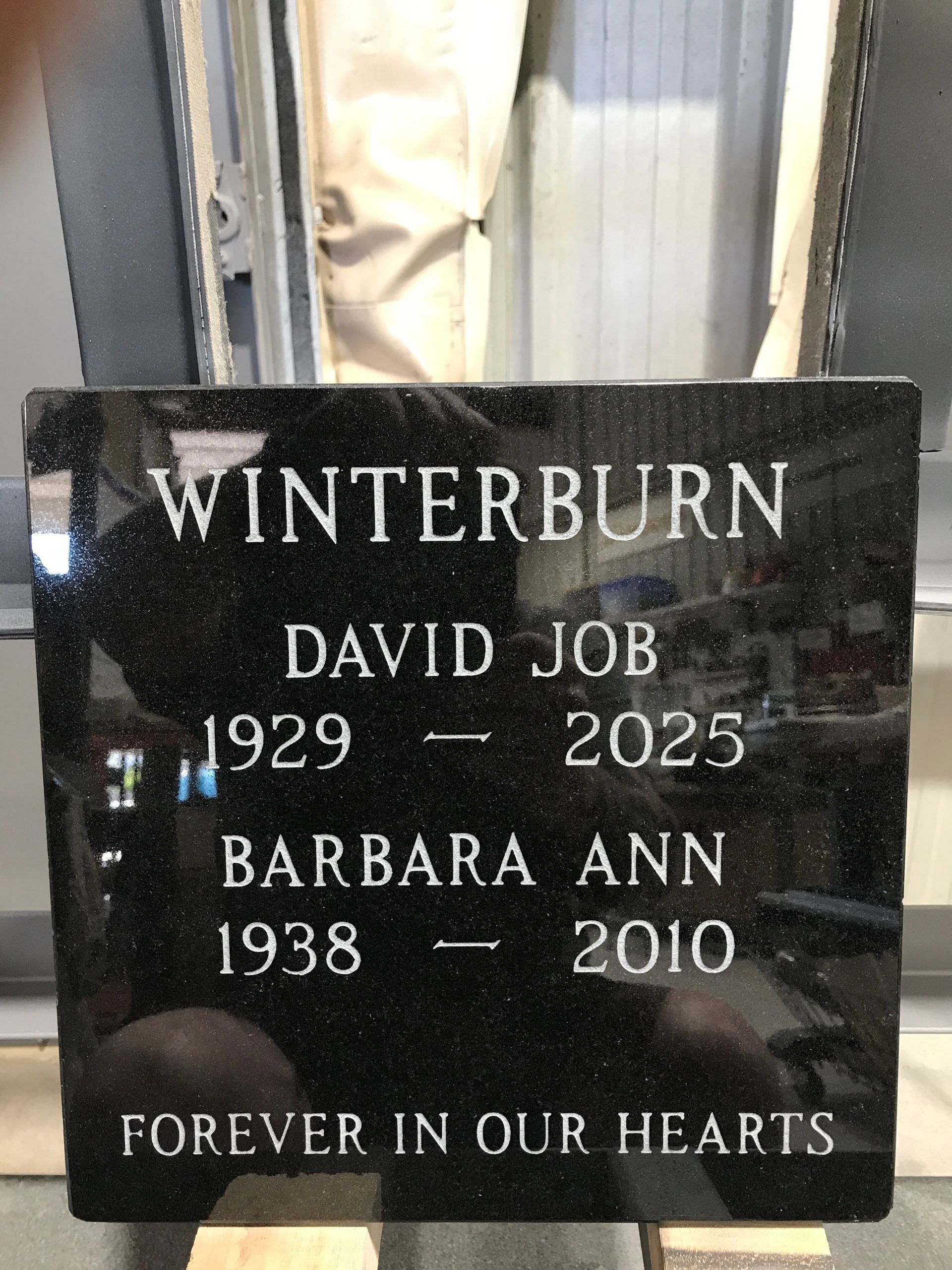 Black granite memorial headstone for Winterburn, honoring David Job and Barbara Ann with dates and “Forever in our hearts.”