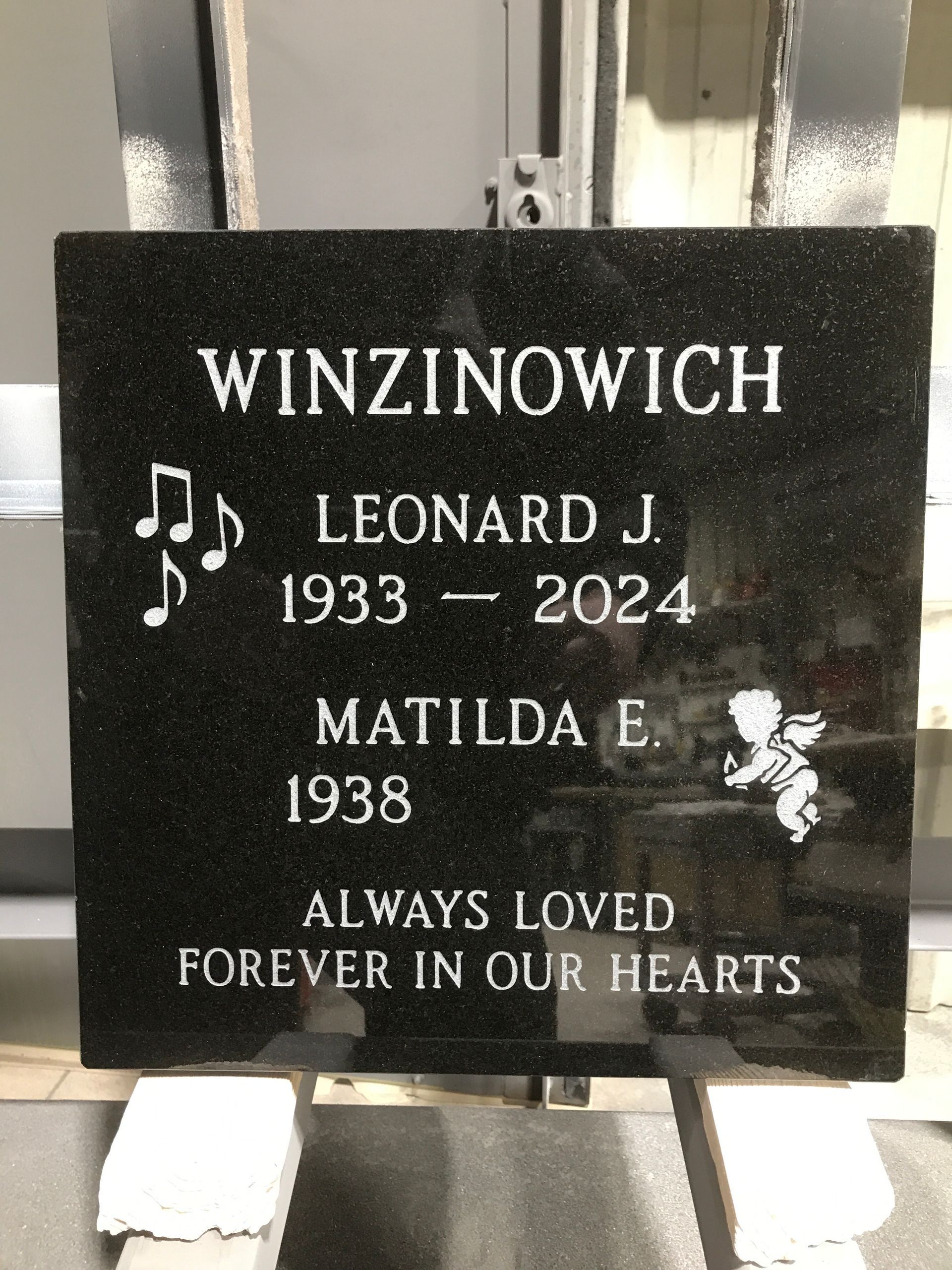Black granite memorial plaque for Leonard J. and Matilda Winzinowich with engraved names and dates.