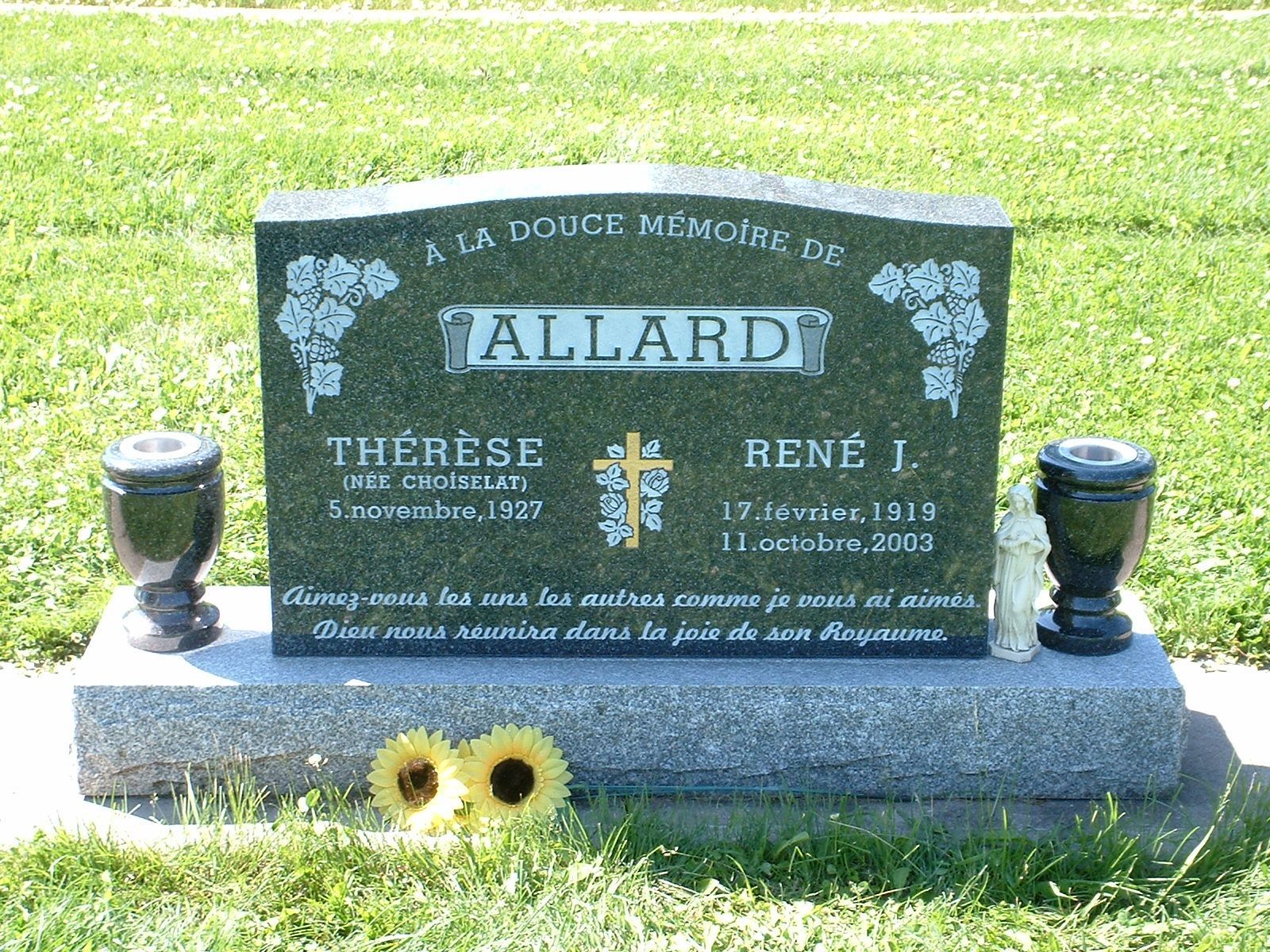 Gravestone for the Allard family with flowers on a grassy cemetery plot.