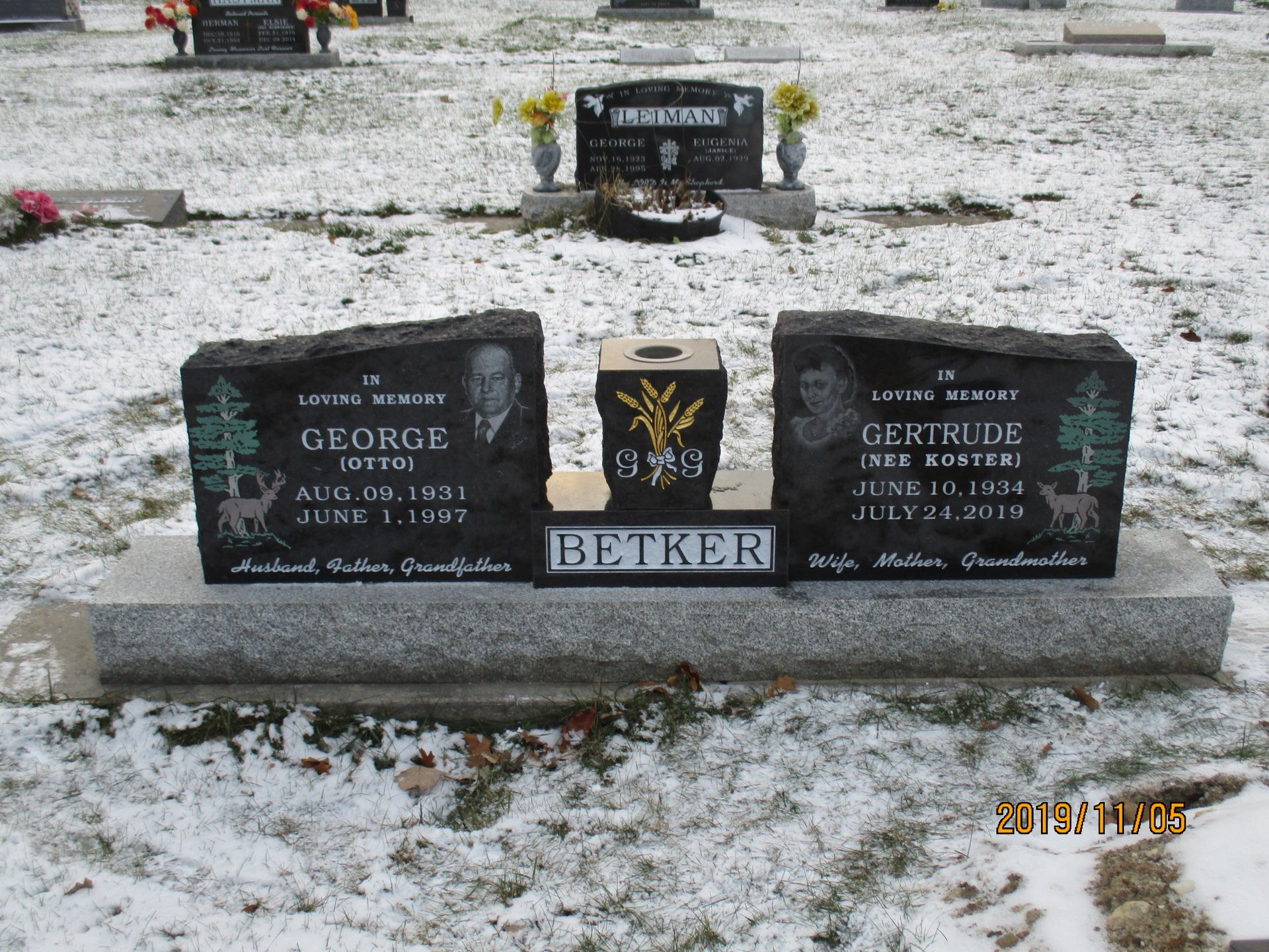 Snow-dusted cemetery grave marker with black plaques and the name BETKER on the base