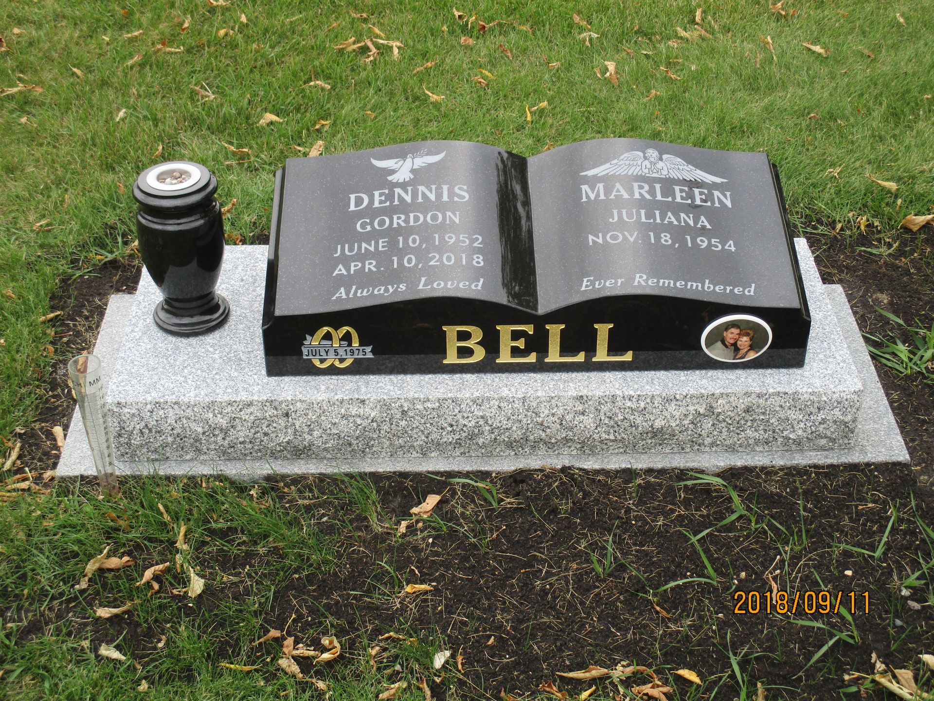 Gravestone with two open-book plaques and the name “Bell” on a lawn in a cemetery