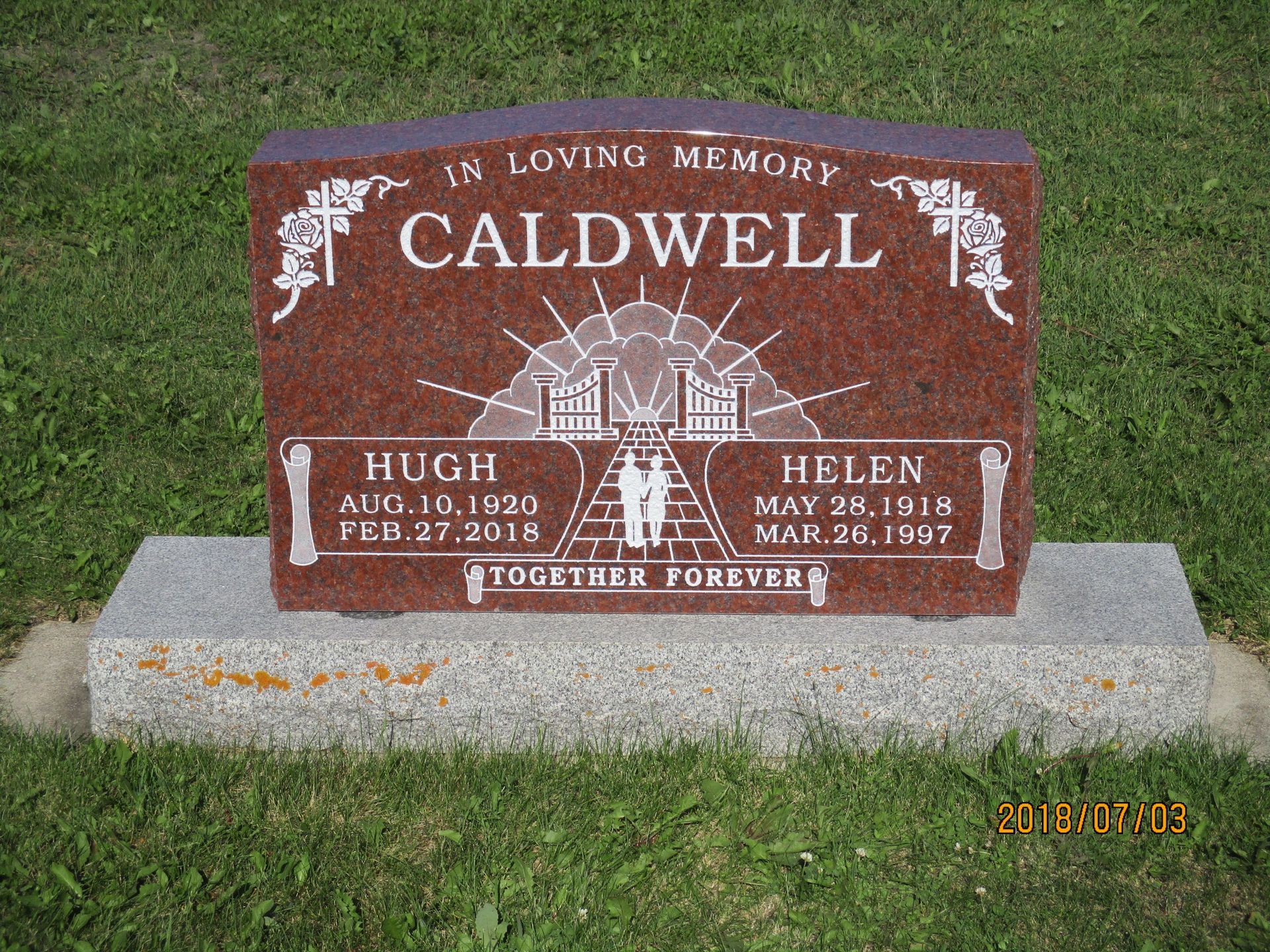Caldwell family gravestone with red granite marker on a concrete base in a grassy cemetery
