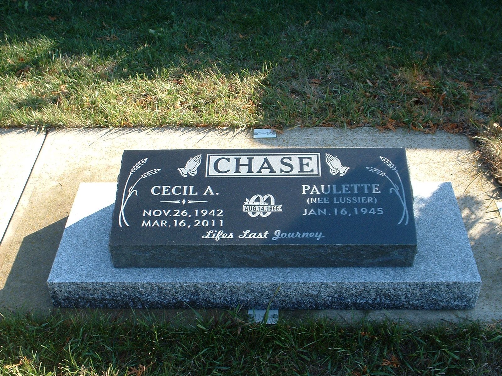 Black granite memorial plaque on a stone base in a grassy outdoor setting, with a “CHASE” nameplate.
