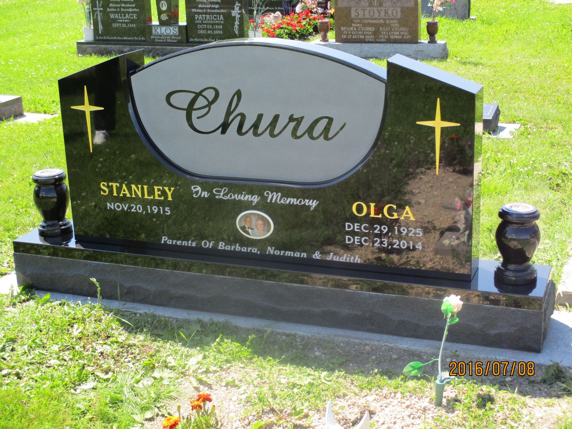 Black granite memorial headstone with gold crosses and the name