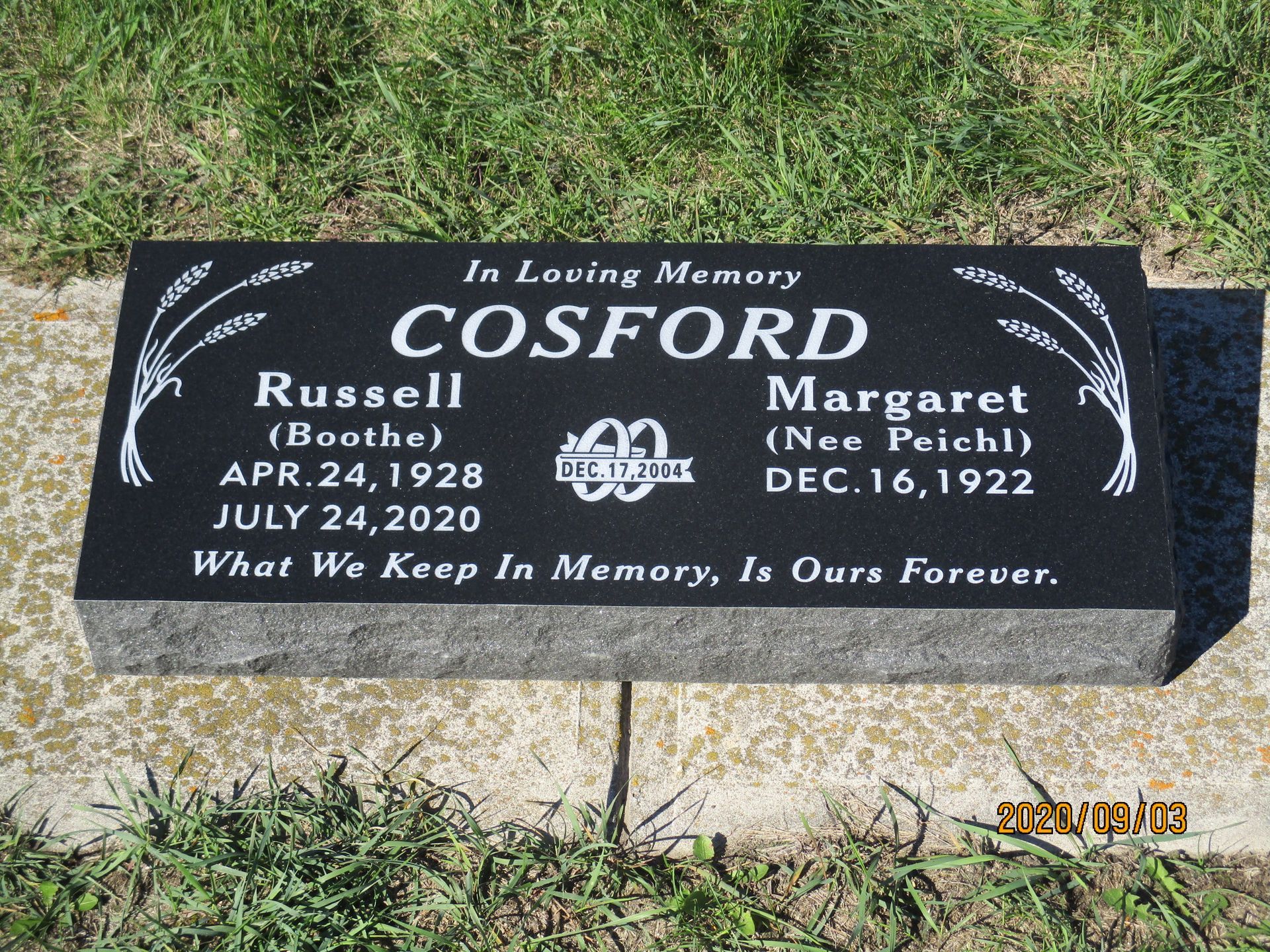 Black granite memorial marker in grass for Russell and Margaret Cosford with names and dates.