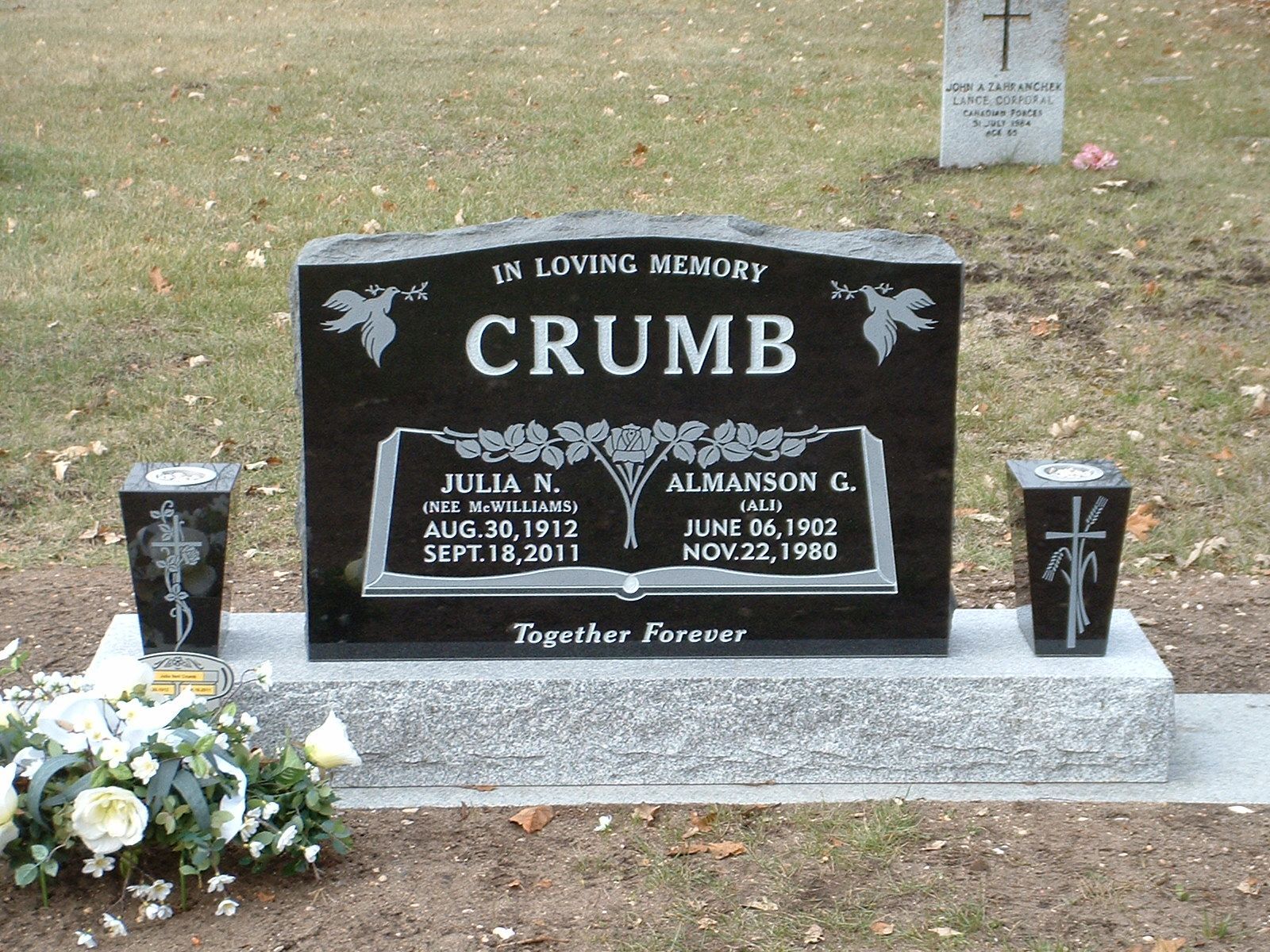 Gravestone for the Crumb family with flowers at the base in a cemetery.