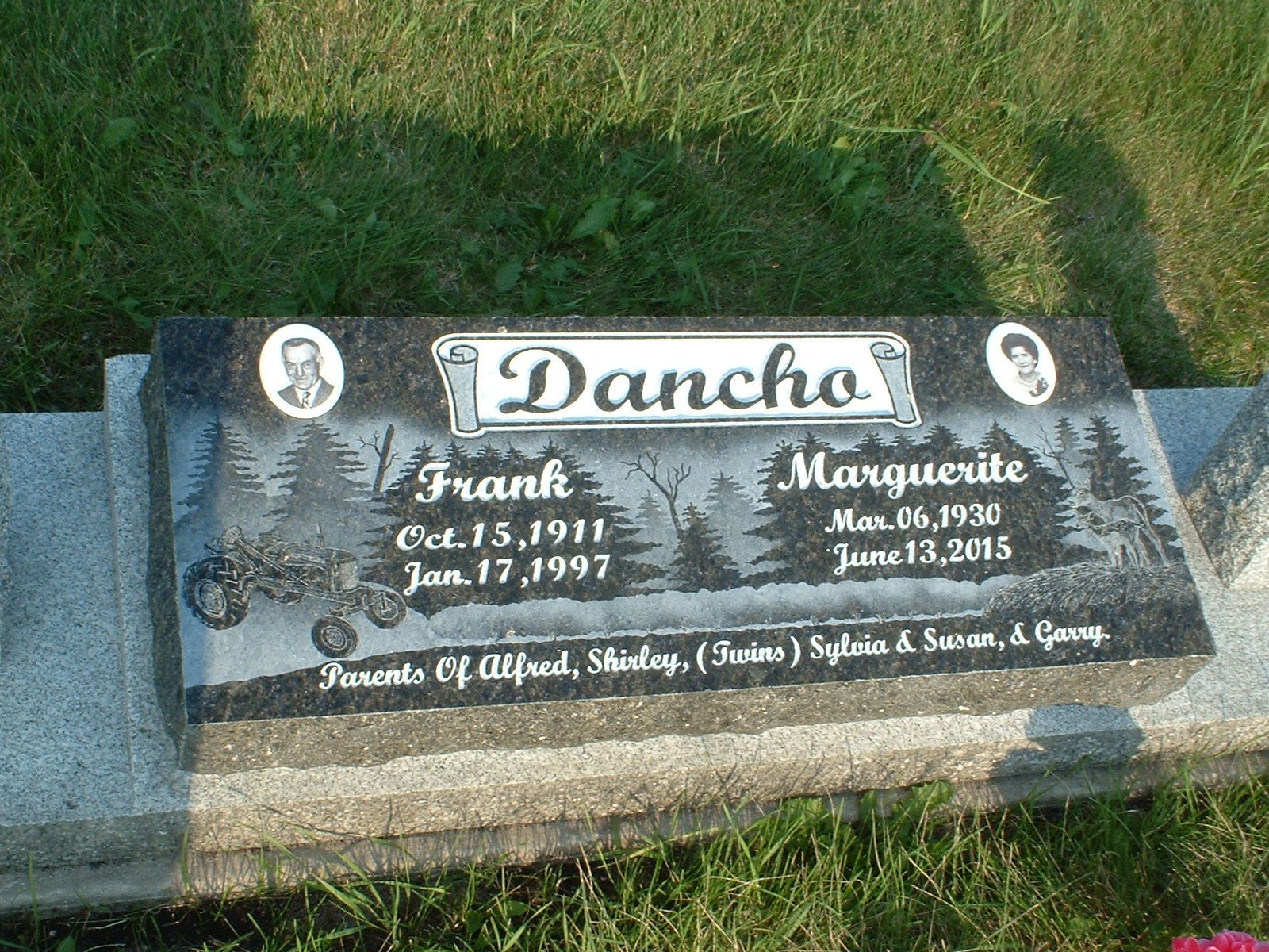 Gravestone in grass with the name “Dancho” and birth and death dates engraved on a dark stone.