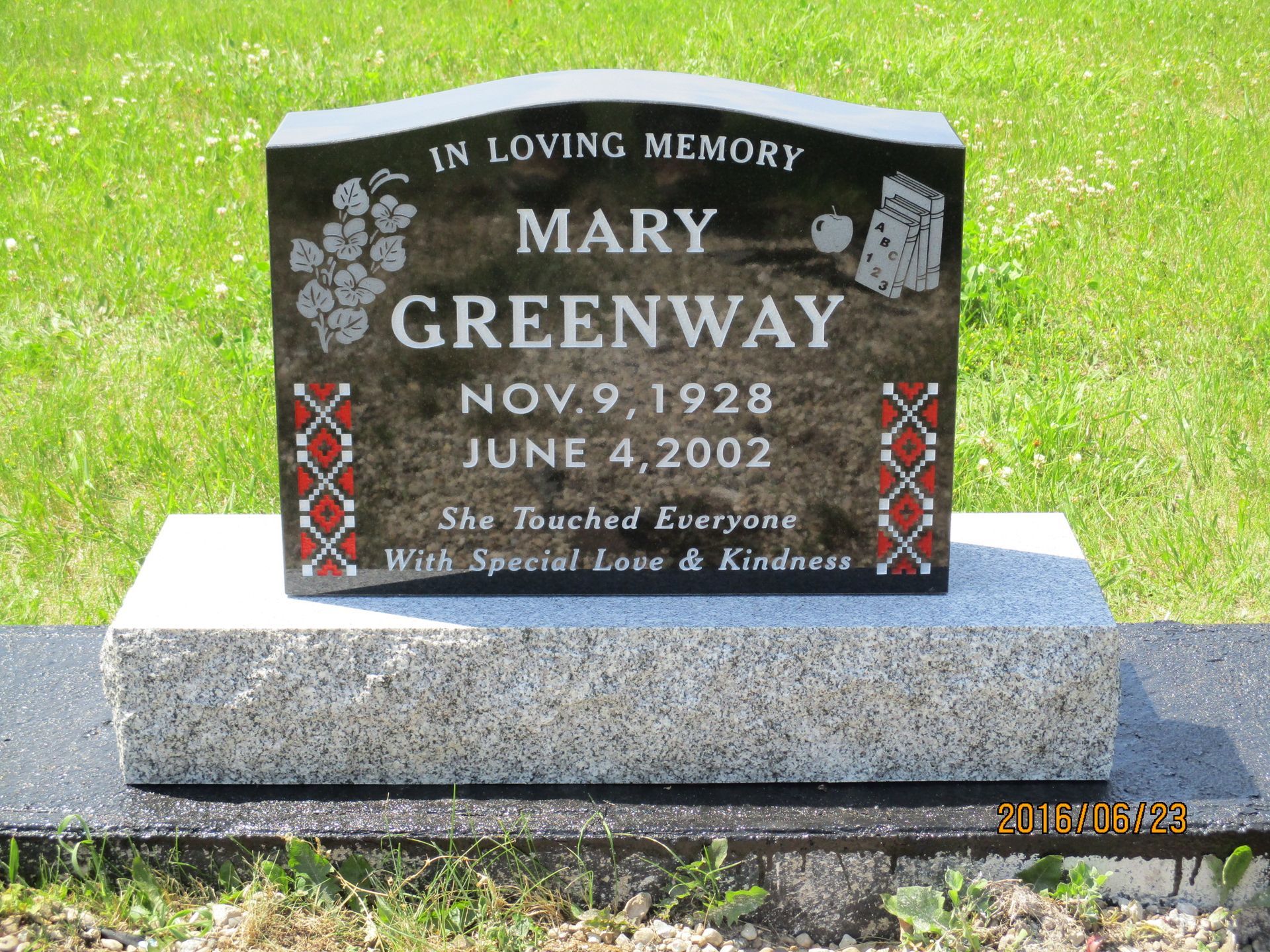 Mary Greenway memorial gravestone with white lettering and red floral accents on a granite base.